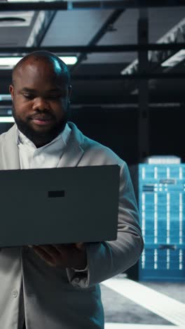 Vertical video Data center engineer coding on laptop, doing software updates for mainframes