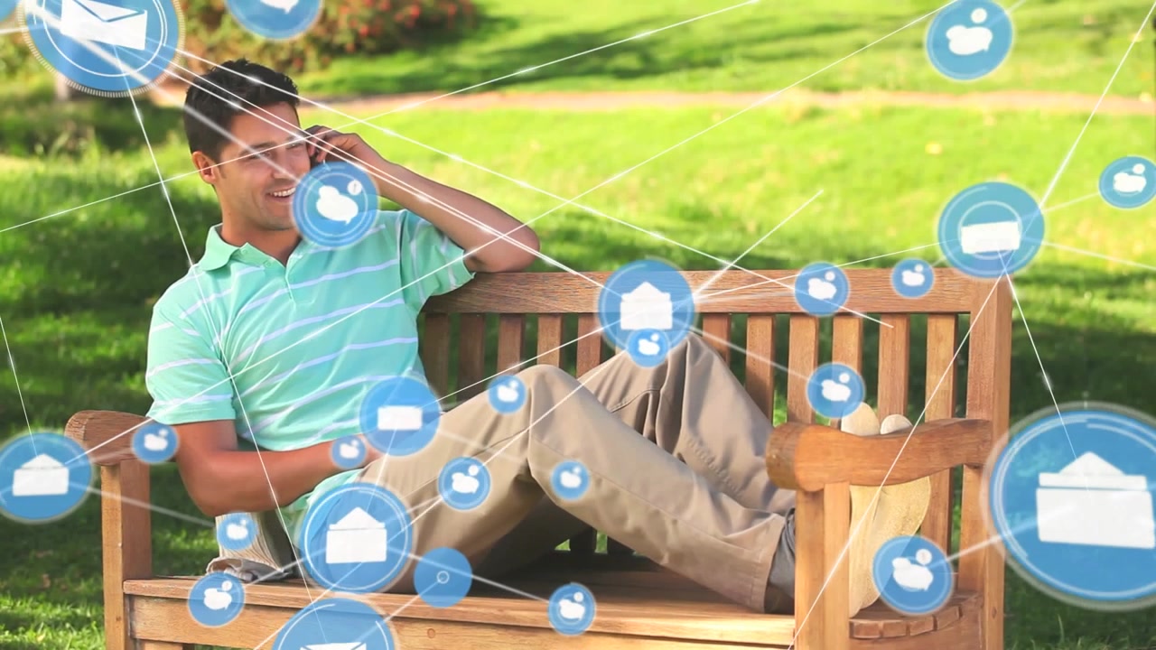 Animation of digital icons over caucasian man talking on smartphone sitting on the bench in tha park