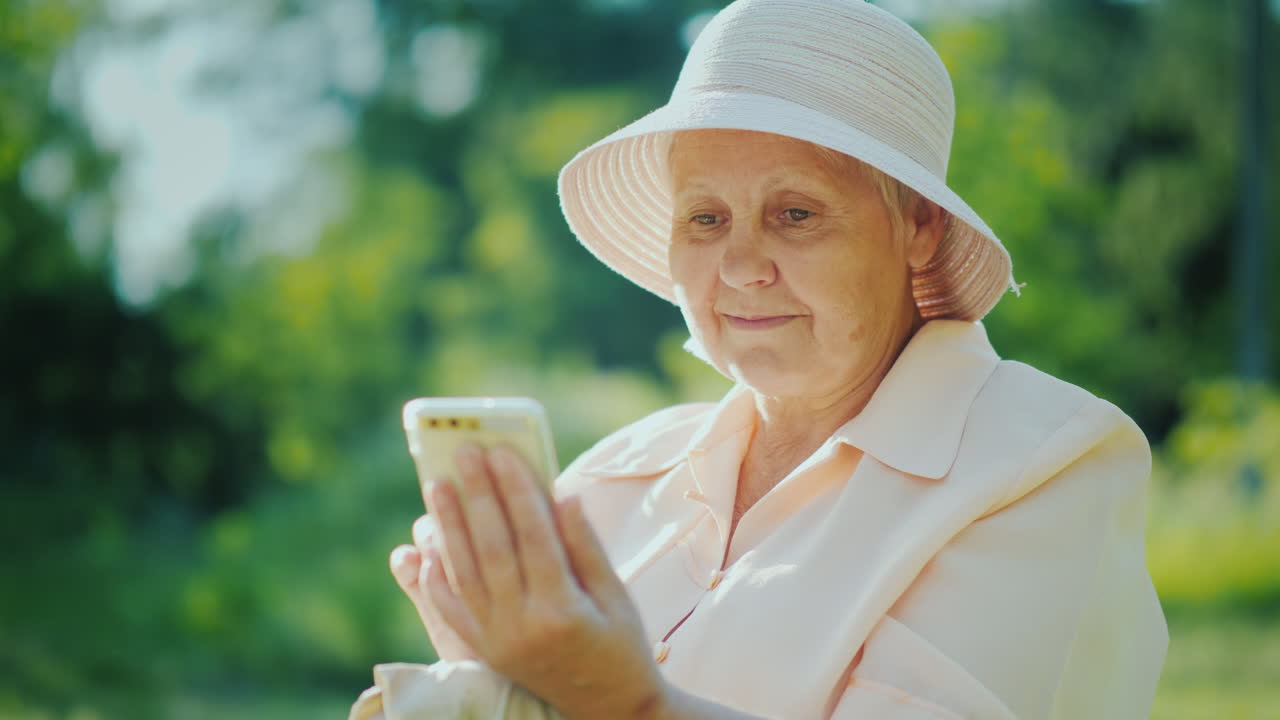 스마트폰 화면을 함께 보고 있는 할머니와 함께 행복한 소녀는 여름에 함께 휴식을 취합니다
