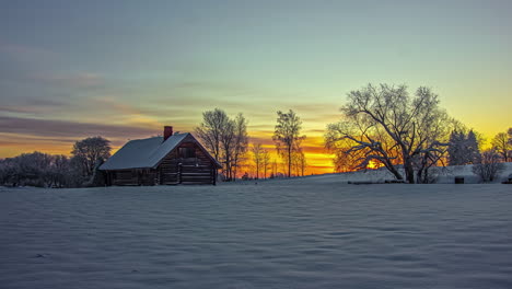 stunningly colorful sunrise beyond a cabin on a winter landscape - time lase