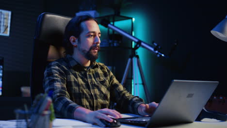 hombre sonriente relajándose en la sala de estar viendo clips divertidos de internet en la computadora portátil