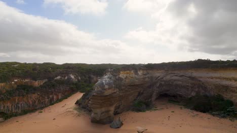 drone footage captures the dramatic cliffs and ocean waves at port campbell, australia, under a partly cloudy sky