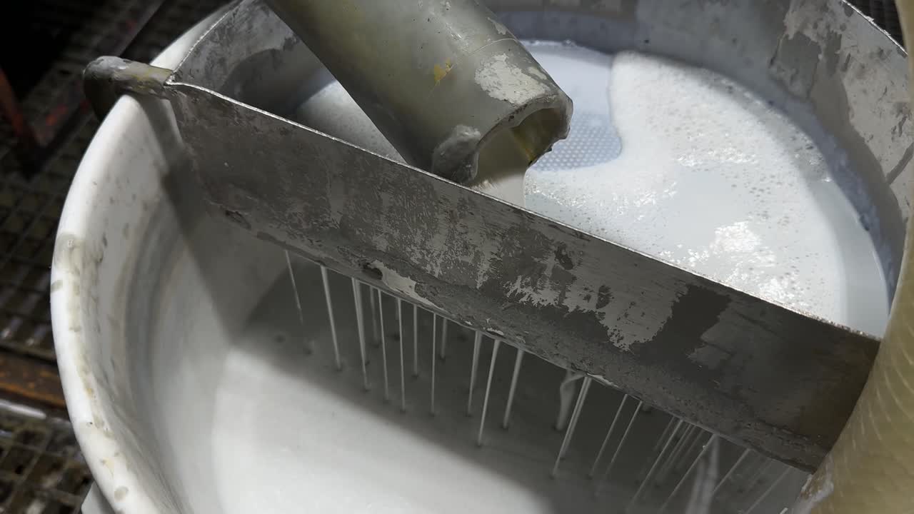 Process involving a white liquid mixture being strained coating paint using a mechanical device