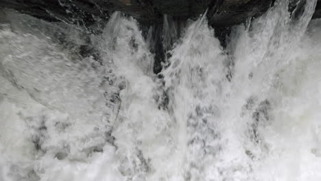 the raging waters of the river alne in warwickshire, england as it passes through sluice gates that control the amount of flood water after torrential rainfall