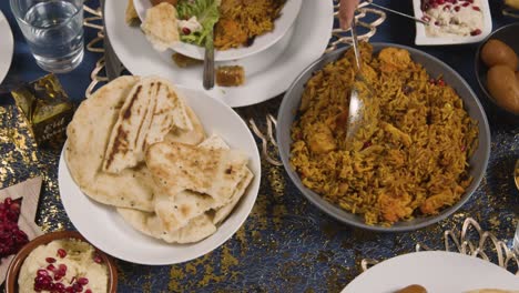 close up of muslim family sitting around table with food for meal celebrating eid being served 3