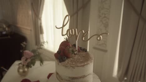 love decoration on cream layered luxury wedding cake centrepiece at marriage banquet slow push in left