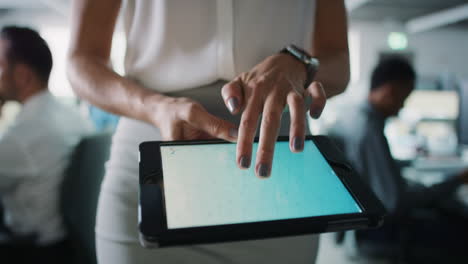 mujer de negocios usando una tableta digital caminando a través de una oficina ocupada con pantalla táctil manipulando la forma 3d