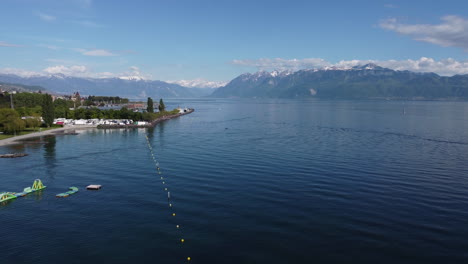 Aerial-rise-of-the-Lake-Geneva-waterfront-near-Lausanne,-Switzerland-on-a-sunny-day