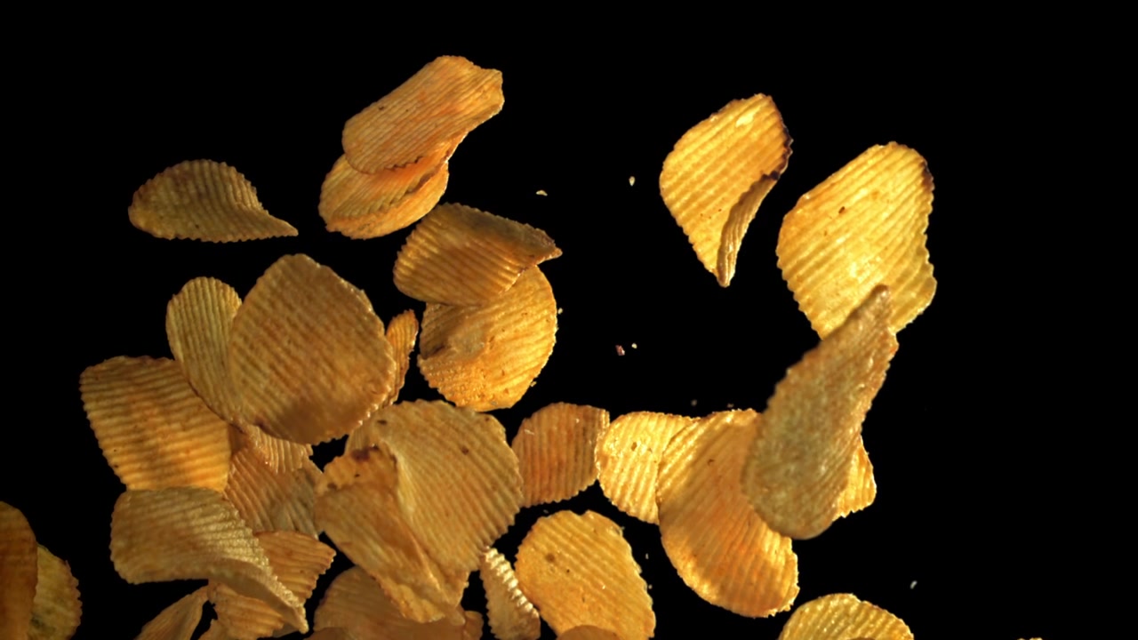 Golden Ruffled Potato Chips Flying and Falling in Slow Motion