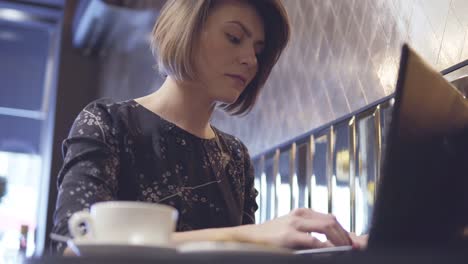 Frau-Arbeitet-An-Ihrem-Laptop-Und-Genießt-Ihren-Kaffee