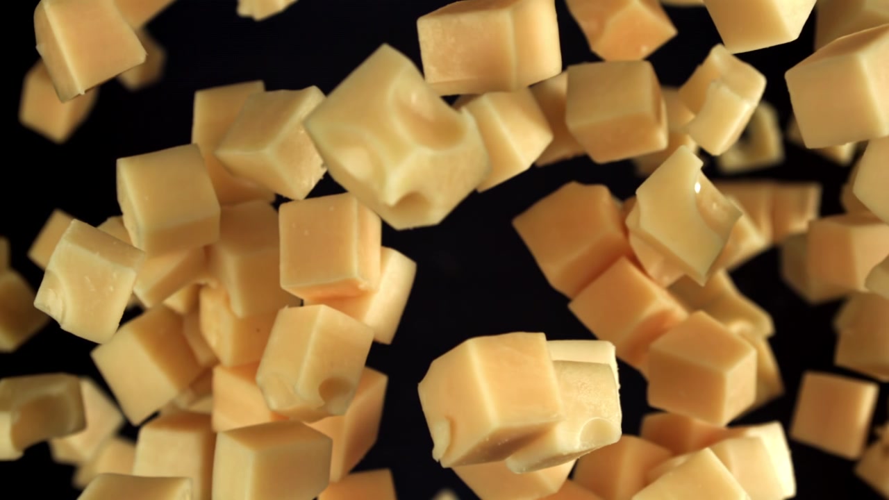 Cubes de fromage tombant au ralenti sur un fond noir