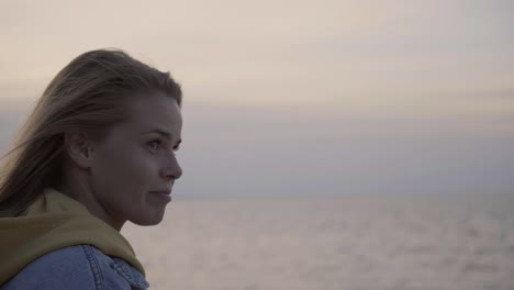 face portrait of young woman at sunset above sea