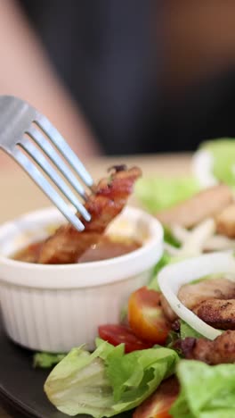 horquilla sumergiendo la carne en la salsa en la ensalada
