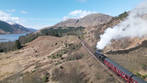 tren de máquina de vapor viajando a través de las tierras altas escocesas en un hermoso día