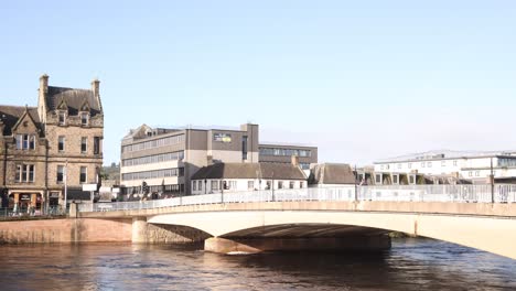 townhomes and storefronts and bridge along rushing river in inverness, scotland in the highlands