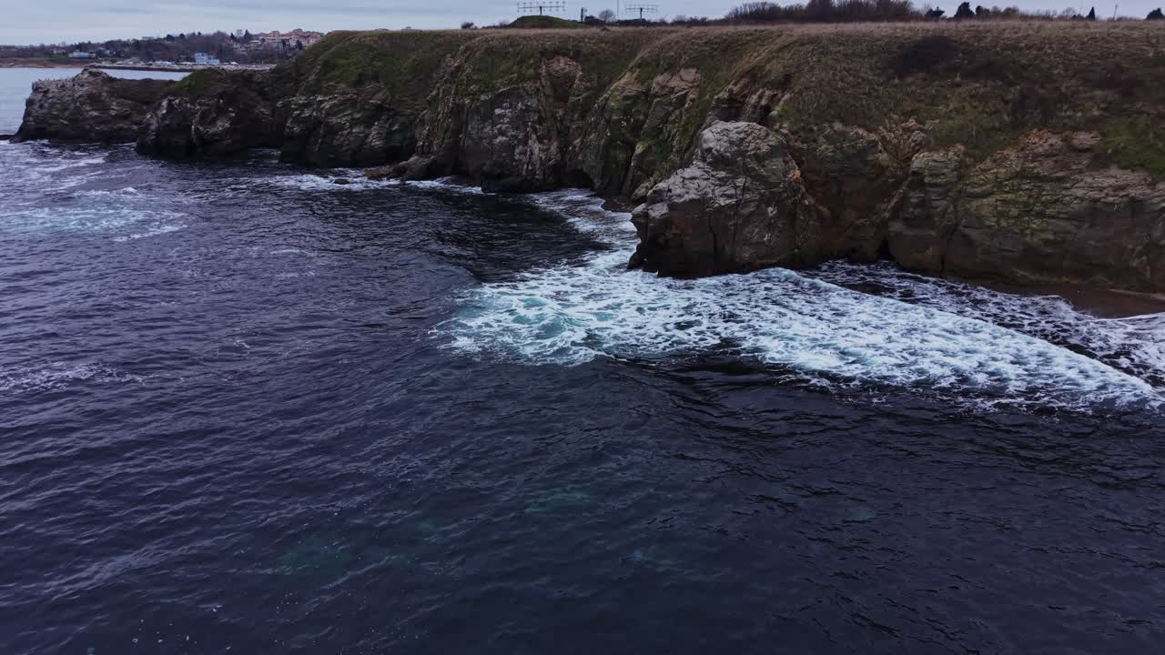 Onde che si infrangono sulla costa rocciosa durante una giornata nuvolosa.