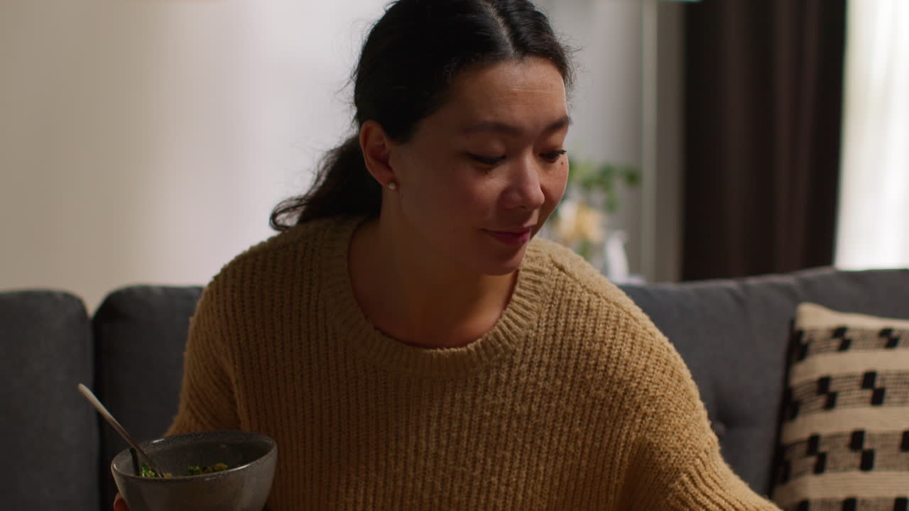 집에서 소파에 앉아 건강한 채식주의자 또는 채식주의자를 먹고 와인 한 잔과 함께 타부레 러드 식사를 하고 노트북에서 쇼를 보고 있는 여성