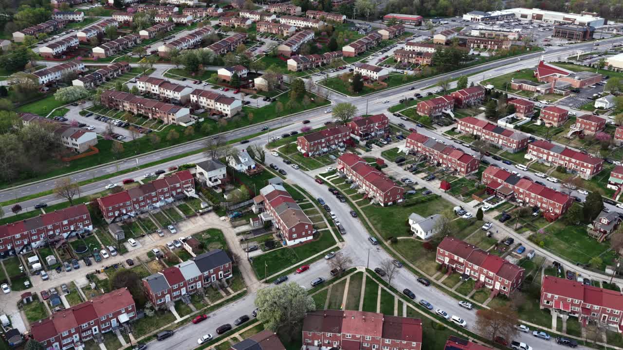 Vista aerea dall'alto di un quartiere residenziale di Baltimora con case a schiera in mattoni, strade che si intersecano e traffico leggero, che mostra la disposizione urbana e suburbana e la densità abitativa nel Maryland, USA.
