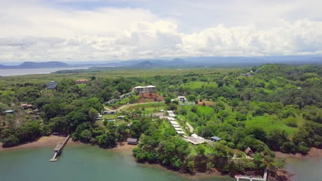 horizontal drone shot of beautiful vacation location next to the sea in a forest with mountain and cloudy sky background, boca, chica, panama