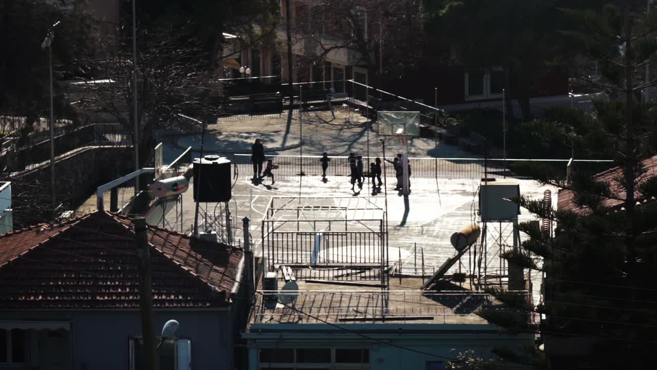 슬로우 모션으로 노는 아이들의 실루엣이 있는 거리 농구 코트