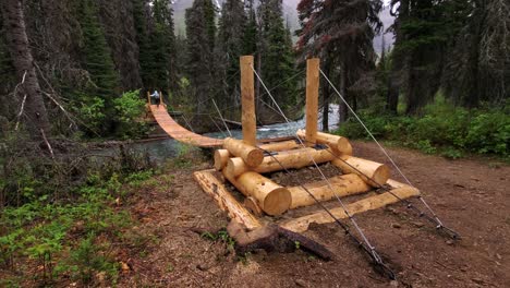 puente colgante de cuerda de madera y excursionista caminando sobre el río en el parque nacional de los glaciares, montana, ee.uu.