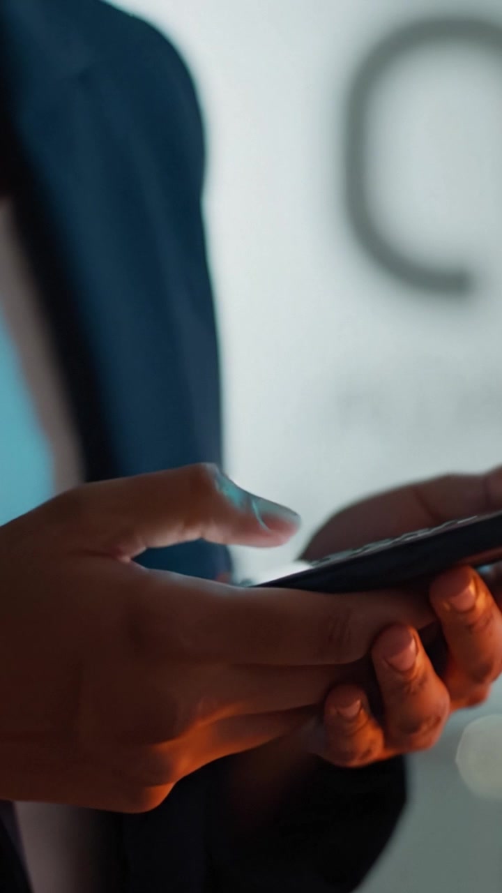 Engaged in Digital Communication: A Close-Up View of Hands Holding a Smartphone, Dressed in Formal Attire, Implying Professional Context in a Modern Environment