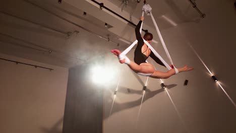 flexible sensual girl practicing in an aerial hammock. low angle