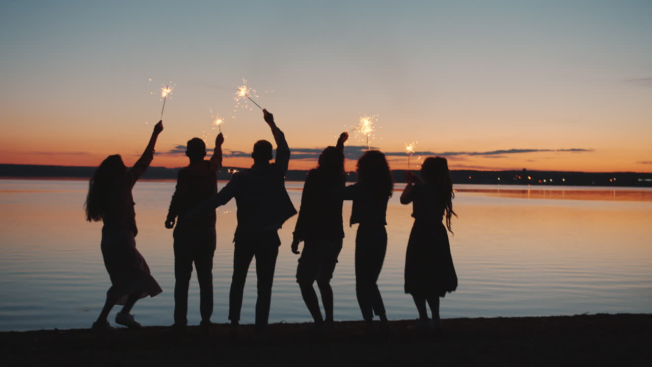 스파클러와 함께 해가 지는 것을 축하하는 친구들