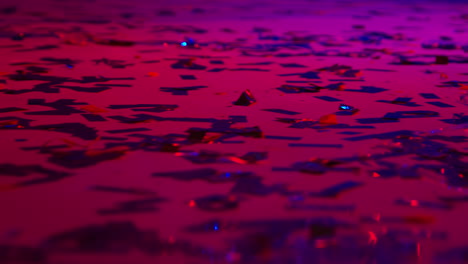 close up of sparkling confetti on floor of nightclub bar or disco with flashing strobe lighting 2