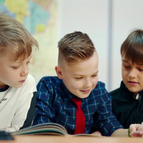 cute boys study at school. schoolchildren reading a book together while sitting in the classroom. primary education at school.