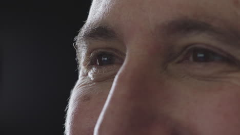 close up of mature man eyes looking smiling happy on black background