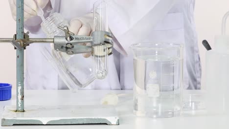 scientist carefully transfers liquid into a test tube using a clamp setup in the laboratory.