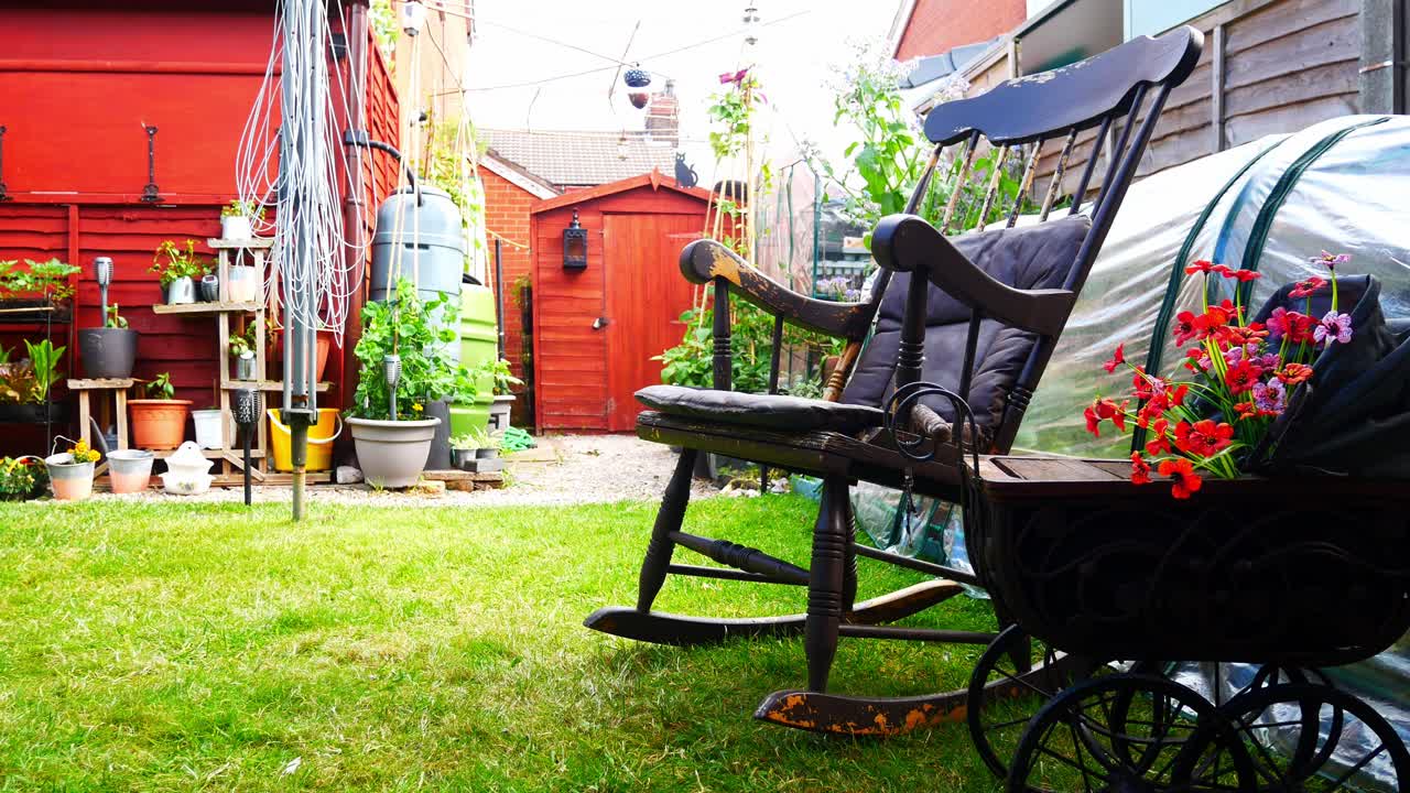 평화로운 영국식 정원 그늘에 풍화된 흔들 의자와 으스스한 고딕 양식의 나무 유모차 화분