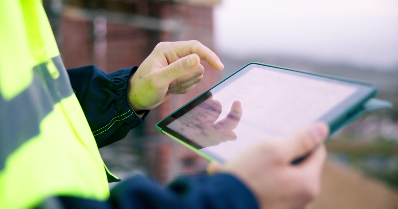 建設現場でデジタルタブレットを使う建設作業員