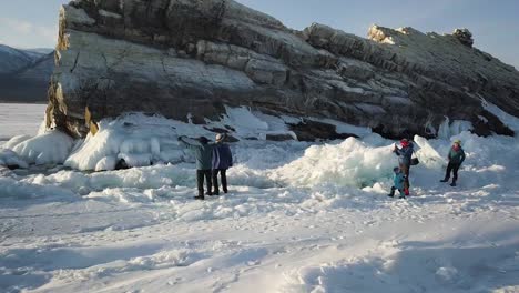 people exploring a frozen lake with ice formations and rocks