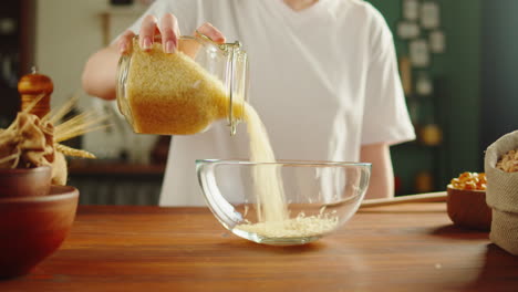 person pouring rice into a glass bowl for cooking