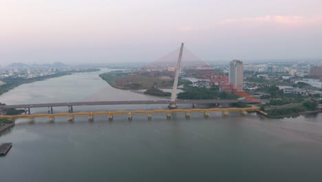 colorful wide aerial of tran thi ly bridge, traffic and city skyline during sunset in danang, vietnam