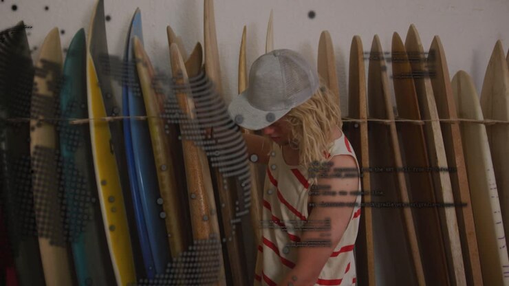 Vertical video: Man checking surfboards reaching rack choosing board dotted overlay covering left