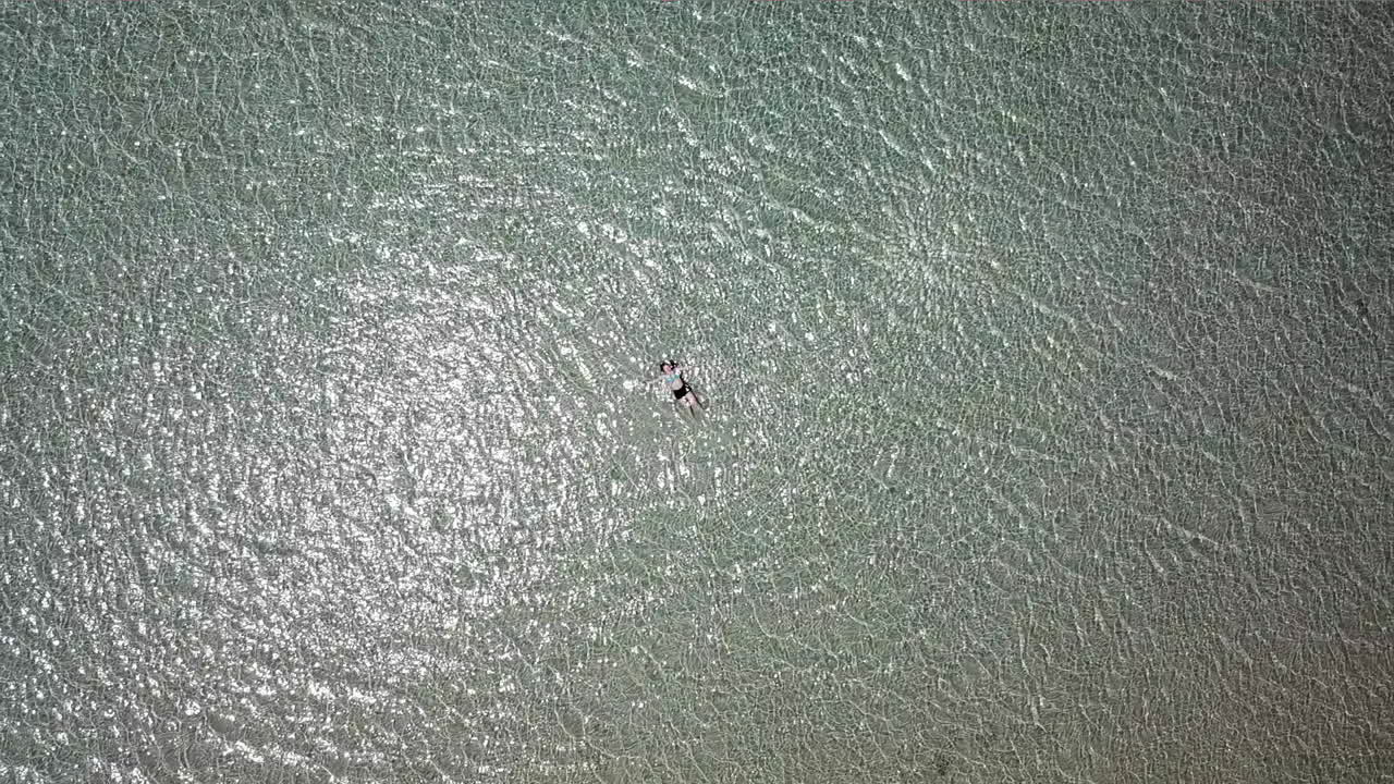 disparo aéreo de una adolescente acostada en aguas poco profundas en una playa