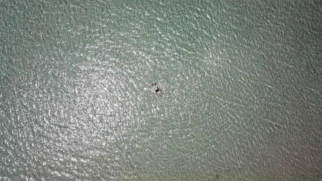 aerial rising shot from a teenage girl lying in shallow water on a beach