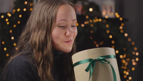 curious woman opens christmas gift and gets surprised, portrait view