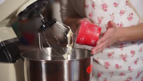 mujer preparando ingredientes para un pastel con un mezclador de soporte