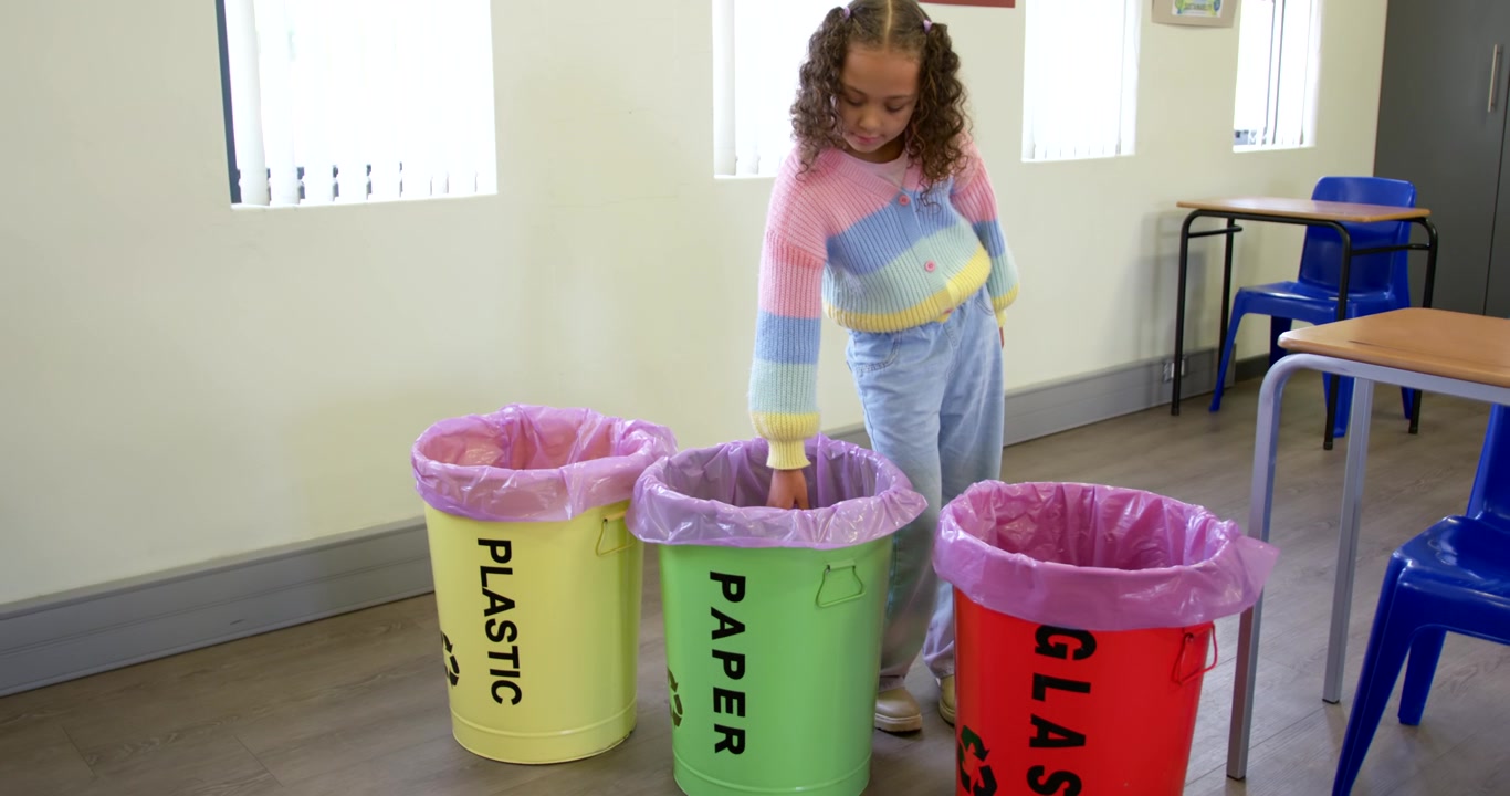 African American child reading PAPER label, placing tube into bin in classroom, recycling, walking
