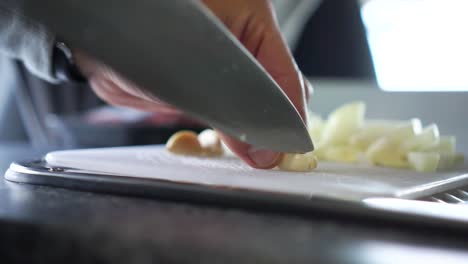 Chef-chopping-garlic-with-knife-on-cutting-board-in-kitchne-of-motorhome---Close-Up