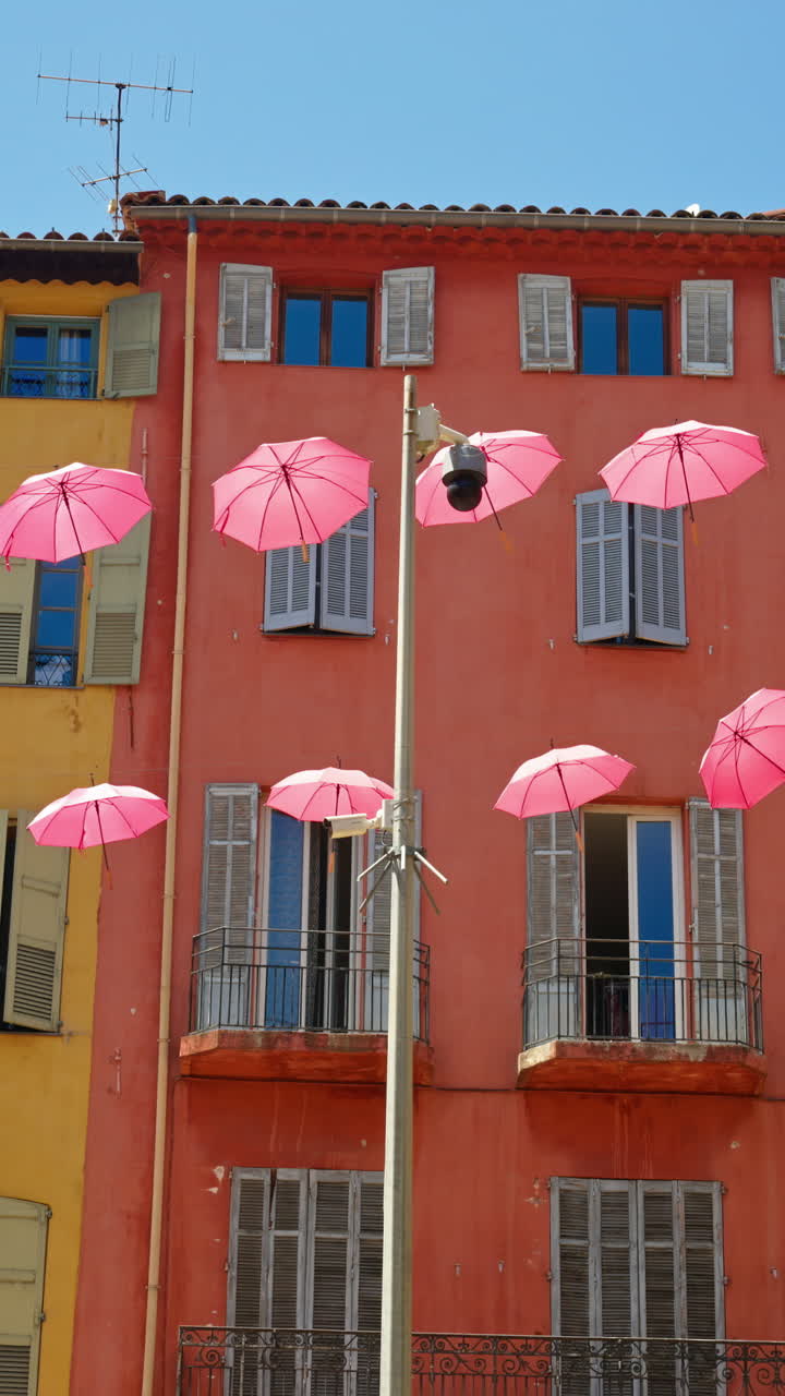 Rows of pink umbrellas above the streets of the old town in Grasse, France. Vertical