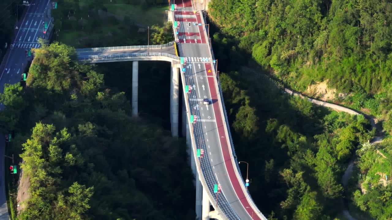 Telephoto drone shot tracking a car driving on a bridge into a tunnel, in China