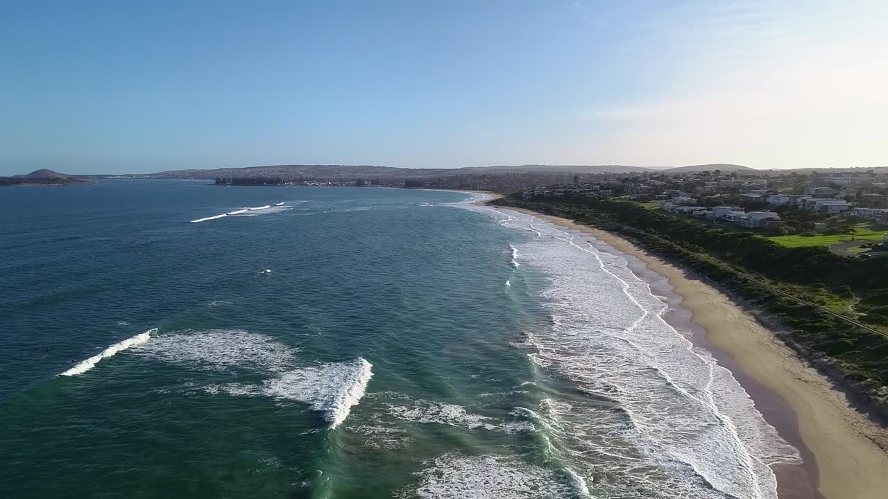 cielo azul sobre las olas del mar en boomer beach y ciudad costera en port elliot, sur de australia