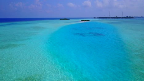 A-Beautiful-Island-With-Blue-Calm-Ocean-and-Bright-Blue-Sky-in-Rasdhoo-Maldives---Aerial-Shot