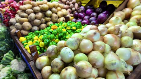 close-up of fresh vegetables including potatoes, peppers, and onions stacked in a vibrant market stall in caracas.