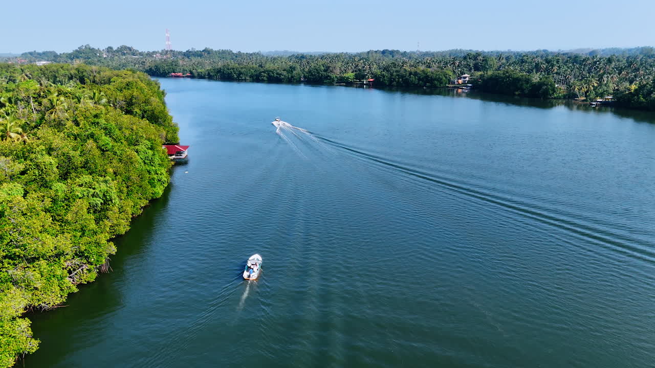 Two boats move by the surface of the river flowing among the picturesque banks. Top view on the nature of Sri Lanka, South Asia on clear sunny day.